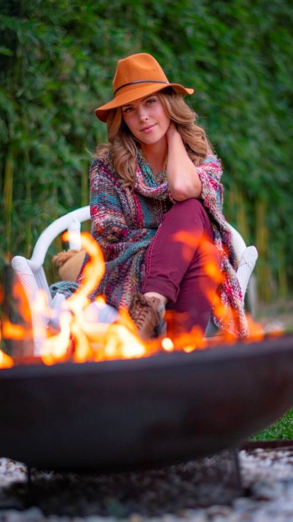 Lady wearing a poncho with a bonfire